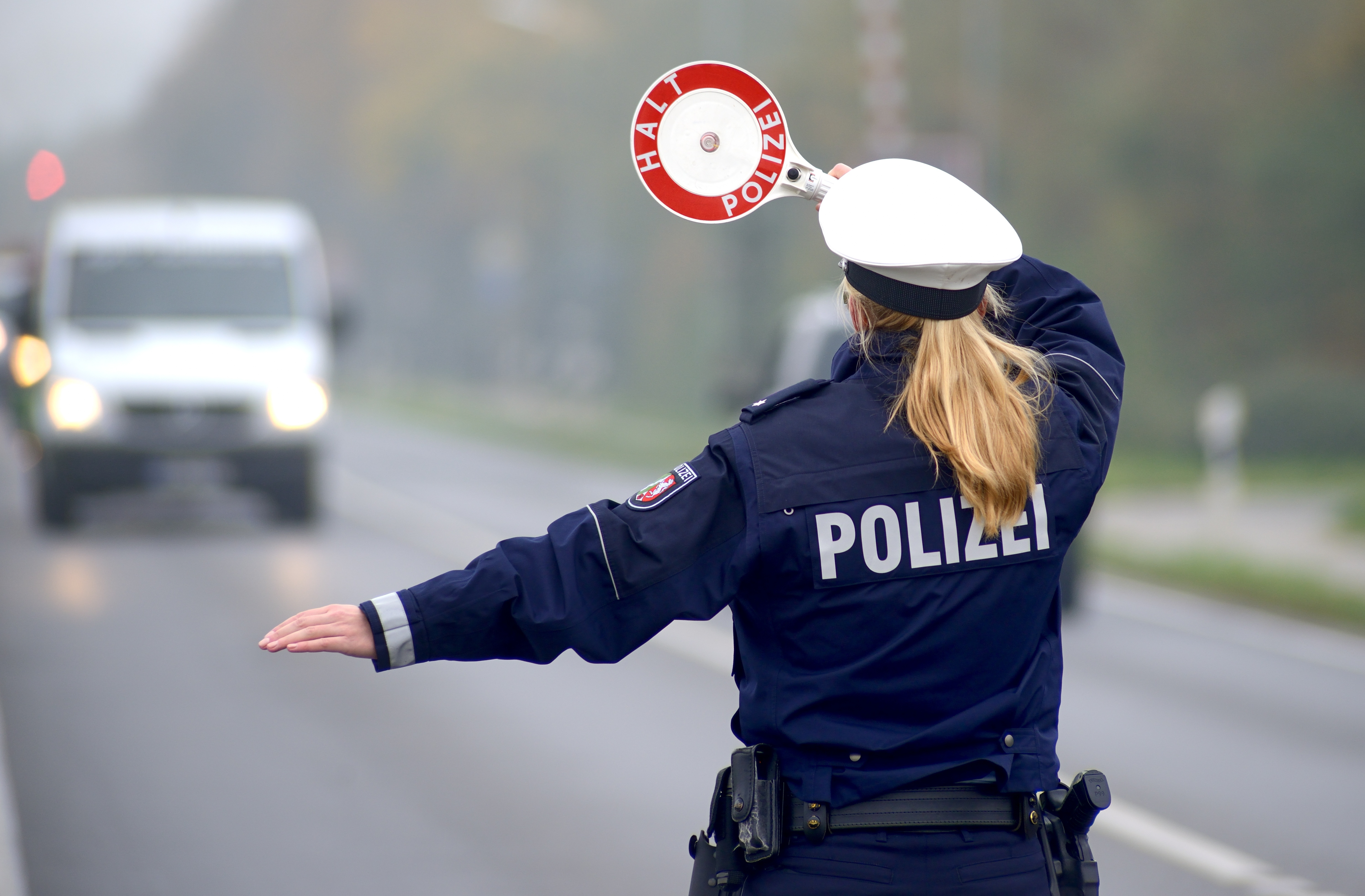 Polizistin hält ein Auto bei einer Verkehrskontrolle an
