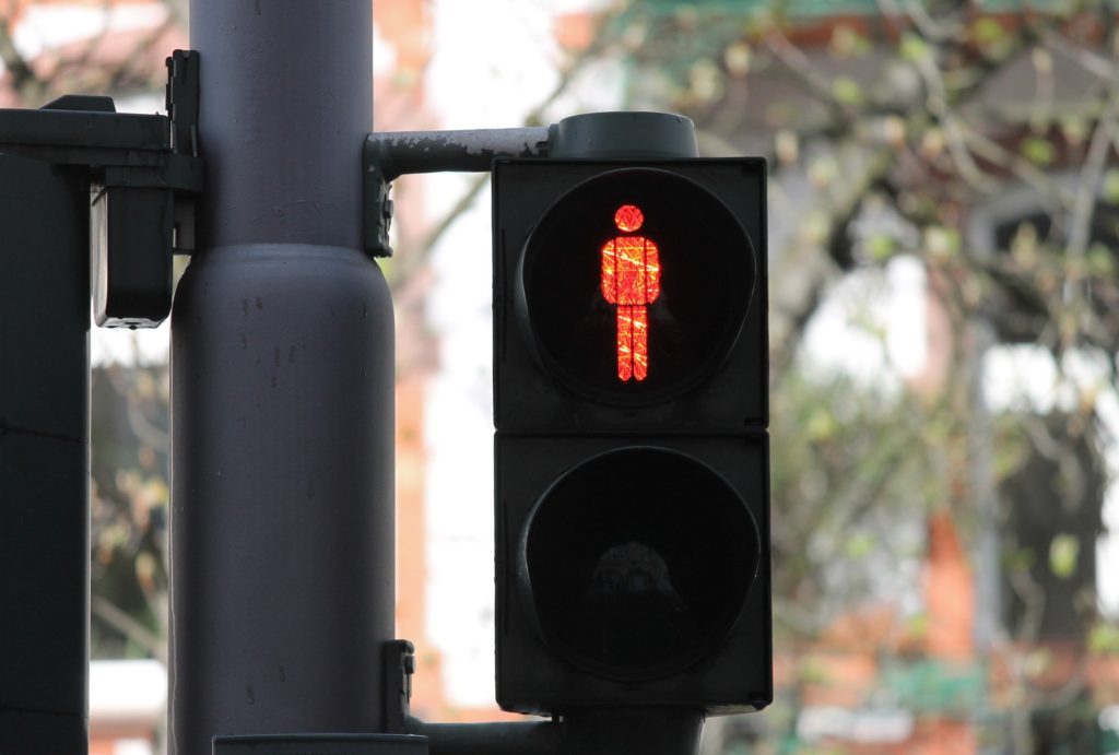 Fußgänger müssen an einer roten Ampel warten, sonst drohen Bußgelder.