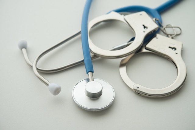 Das Foto zeigt Stethoskop und Handschellen und symbolisiert damit das Medizinstrafrecht (Arztstrafrecht).